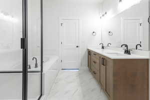 Bathroom featuring double vanity, a bath, marble finish floor, and a sink