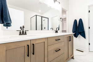 Bathroom featuring double vanity, a stall shower, and marble finish flooring