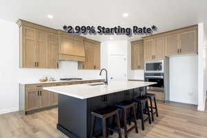 Kitchen featuring stainless steel appliances, custom range hood, decorative backsplash, light wood finished floors, and recessed lighting