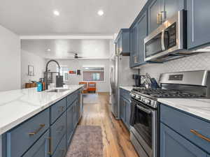 Kitchen with stainless steel appliances, blue cabinetry, and backsplash