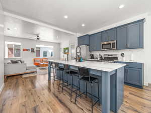 Kitchen featuring decorative backsplash, a large island with sink, a breakfast bar, stainless steel appliances
