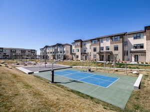 View of home's community with a lawn and sport court