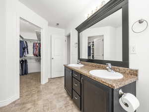 Full bath featuring a walk in closet, double vanity, visible vents, and a sink