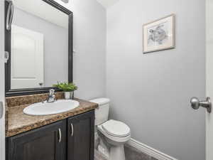 Bathroom featuring baseboards, wood finished floors, vanity, and toilet