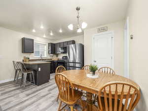 Dining space with an inviting chandelier, light wood-style flooring, baseboards, and recessed lighting