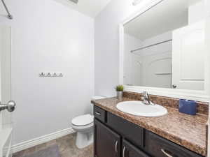 Bathroom featuring stone finish flooring, baseboards, toilet, and vanity