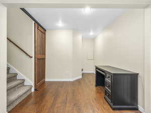 Interior space with a barn door, baseboards, and wood finished floors