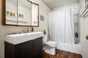 Full bath with shower / bath combo, toilet, vanity, and wood finished floors