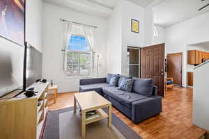 Living room featuring baseboards, wood finished floors, and a high ceiling