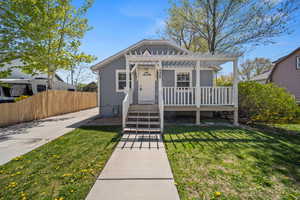 Bungalow-style home featuring a pergola, covered porch, a front lawn, and fence