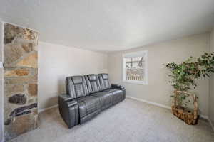 Living area with baseboards, carpet floors, and a textured ceiling