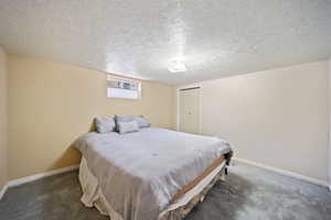 Carpeted bedroom featuring a closet, a textured ceiling, and baseboards