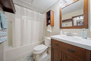 Full bath with tile patterned flooring, shower / bathtub combination with curtain, toilet, vanity, and baseboards