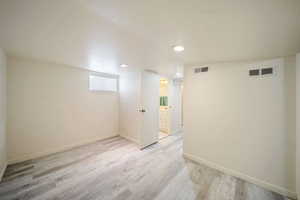 Basement featuring light wood-type flooring, baseboards, and visible vents