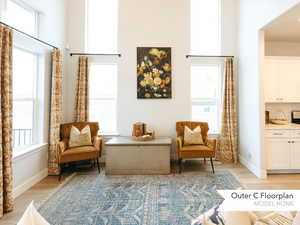 Sitting room featuring baseboards, a high ceiling, and light wood-style floors