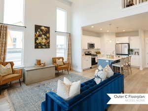 Living area featuring light wood-type flooring, a high ceiling, and a healthy amount of sunlight