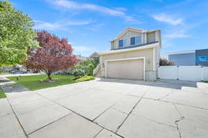 Traditional-style house with a gate, a front lawn, driveway, an attached garage, and fence