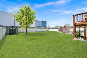 View of yard with a fenced backyard, a wooden deck, an outbuilding, and a storage unit