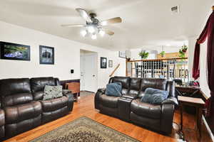 Living area with ceiling fan, wood finished floors, and visible vents