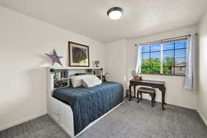 Carpeted bedroom featuring baseboards and a textured ceiling