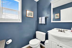 Half bath featuring baseboards, vanity, and toilet