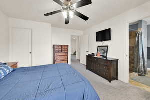 Carpeted bedroom featuring ensuite bath, a ceiling fan, and baseboards