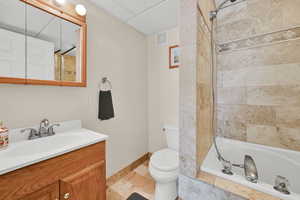 Bathroom with toilet, vanity, baseboards, visible vents, and a paneled ceiling