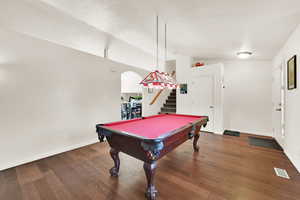 Game room with arched walkways, wood finished floors, visible vents, and baseboards