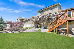 Rear view of house featuring a lawn, fence, a deck, and stairway