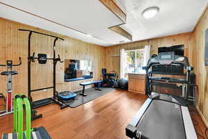 Workout room with wood walls, visible vents, wood finished floors, and a textured ceiling