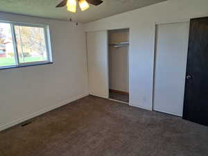 Unfurnished bedroom with a ceiling fan, visible vents, carpet floors, and a textured ceiling
