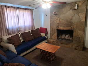 Living area featuring a fireplace, carpet floors, and ceiling fan