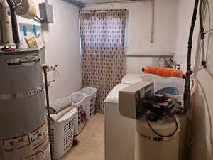 Laundry room with washing machine and dryer, strapped water heater, and laundry area