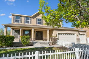 View of front facade featuring a fenced front yard, concrete driveway, a porch, a garage, and stucco siding