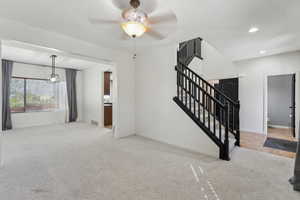 Unfurnished living room with carpet flooring, baseboards, recessed lighting, a ceiling fan, and stairway