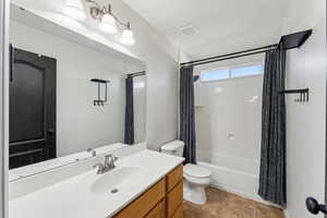 Bathroom featuring tile patterned floors, toilet, visible vents, shower / tub combo, and vanity