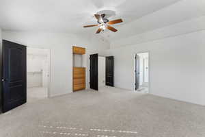 Unfurnished bedroom with connected bathroom, a walk in closet, a closet, baseboards, and light colored carpet