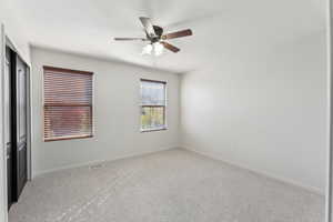 Carpeted spare room with visible vents, baseboards, and ceiling fan
