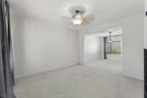 Unfurnished room featuring light colored carpet, baseboards, and a ceiling fan