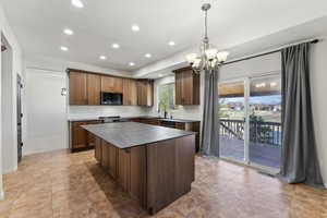 Kitchen featuring a center island, a sink, stainless steel microwave, recessed lighting, and an inviting chandelier