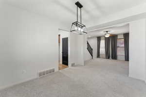 Unfurnished room with visible vents, baseboards, carpet flooring, stairs, and ceiling fan