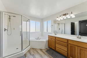 Bathroom with a shower stall, a garden tub, wood finished floors, a sink, and double vanity