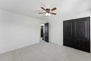 Unfurnished bedroom with ceiling fan, carpet floors, a closet, and baseboards