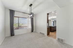 Unfurnished room with visible vents, an inviting chandelier, and light colored carpet