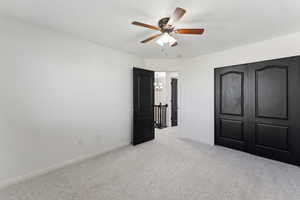 Unfurnished bedroom featuring light carpet, a ceiling fan, and baseboards