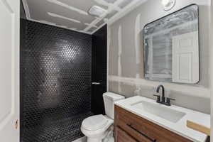 Bathroom with toilet, vanity, and a stall shower