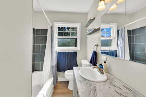 Full bathroom featuring wood finished floors, toilet, vanity, and shower / bath combination with curtain