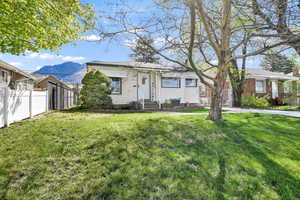 View of front of house with central air condition unit, fence, entry steps, and a front yard