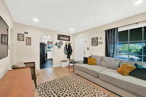 Living area featuring light wood-style flooring, arched walkways, recessed lighting, and a healthy amount of sunlight
