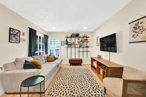 Living area featuring light wood finished floors, baseboards, a textured ceiling, and recessed lighting